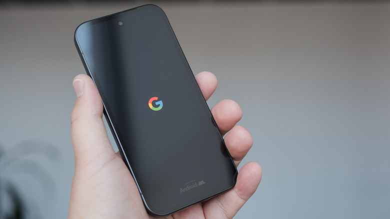a person holding a Google Pixel 9a with the G logo in the middle