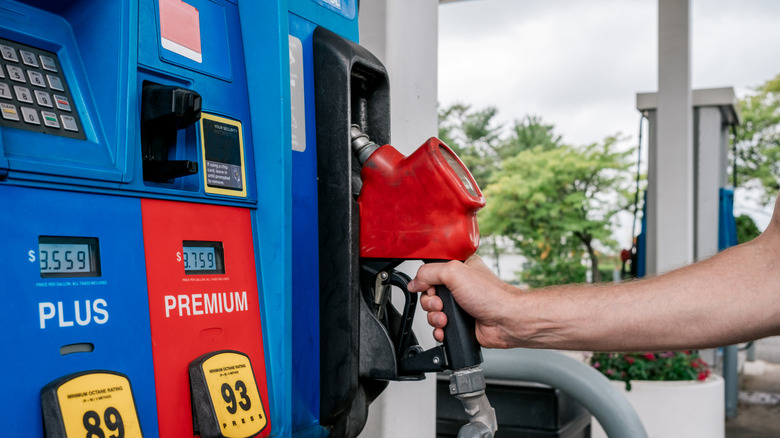 A photo of a man holding a gas pump.