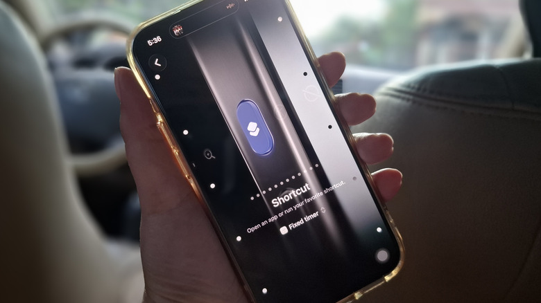 Hand holding iPhone showing Action Button set to shortcut for timer