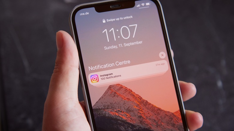Holding an iPhone with notifications displayed on the lockscreen