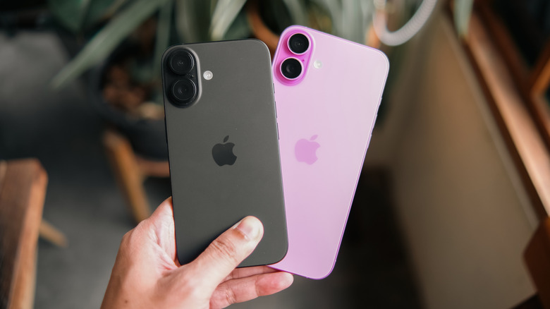 A hand holding a pair of iPhones