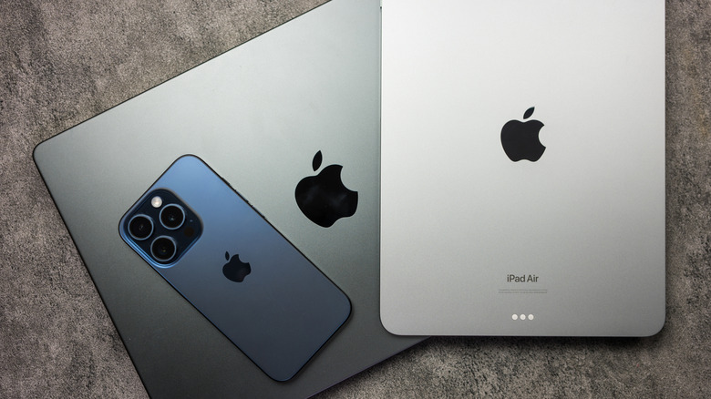An iPhone, iPad, and MacBook on a stone background