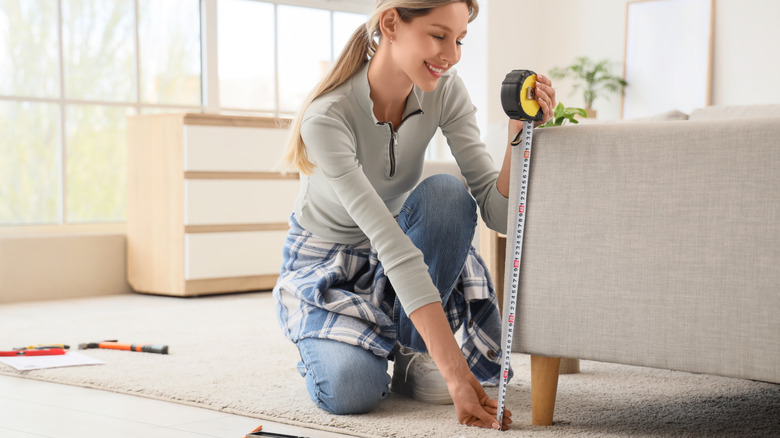 Woman measuring sofa with tape measure