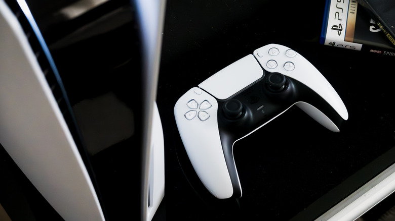 PlayStation 5 next to DualSense controller and game case on black table