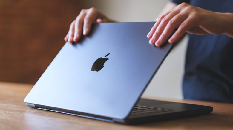 A woman opening or closing an Apple MacBook Pro laptop computer, getting ready for work