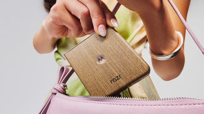 person putting Motorola Razr 2026 into pink bag