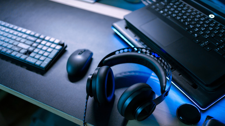 A desk setup with a laptop, keyboard, headphones, and mouse