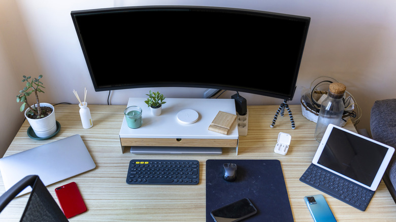 A computer desk setup with a monitor, laptop, and a tablet with keyboard