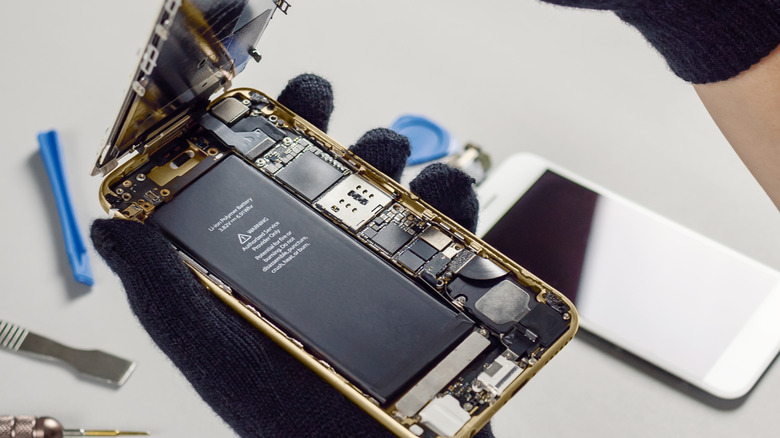 Opening a smartphone, revealing its battery.