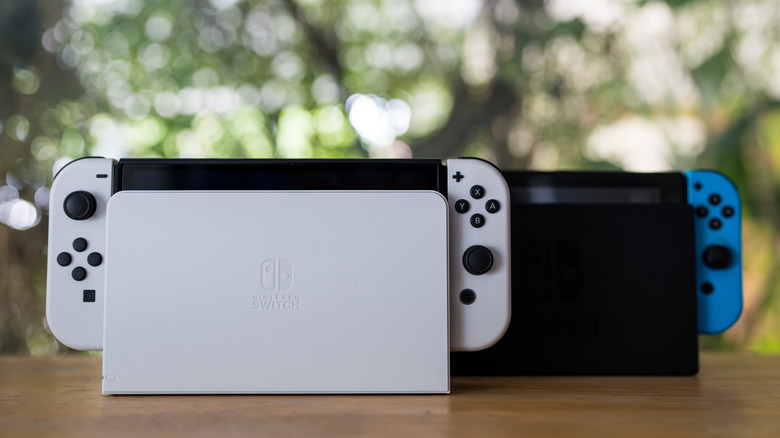 Nintendo Switch models resting on their charging docks outdoors.