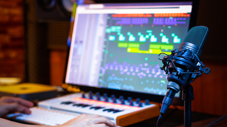 Desktop condenser microphone next to a laptop with audio software open