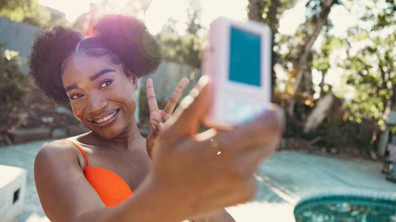 Person using retro 2000s digital camera to take selfie