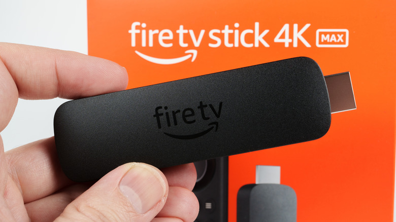 A person holds up a new fireTV stick in front of its box.