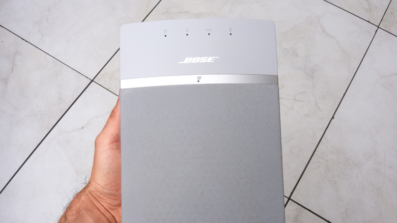 hand holding bose soundtouch speaker over a tiled floor