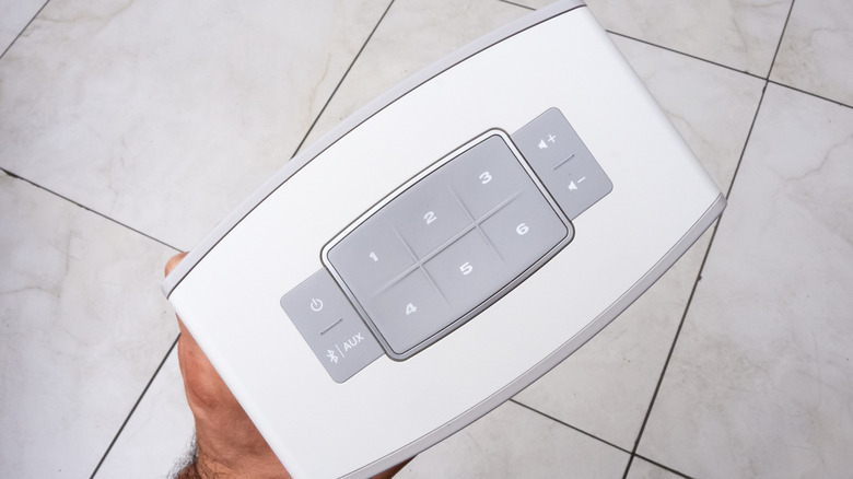 hand holding bose soundtouch speaker over a tiled floor