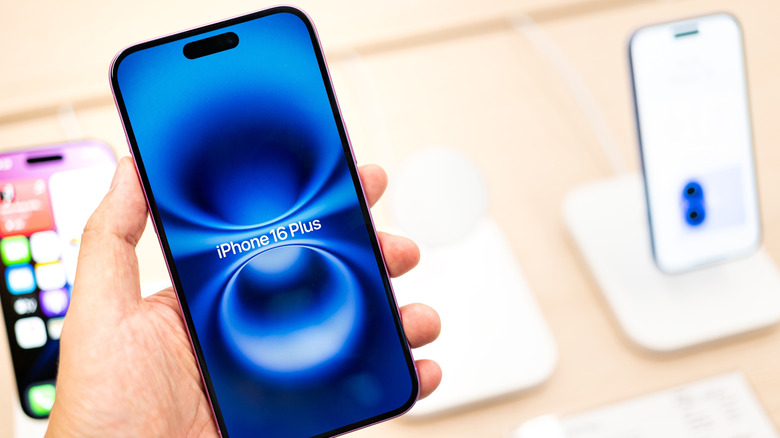 The iPhone 16 Plus demo store unit held by a human hand.