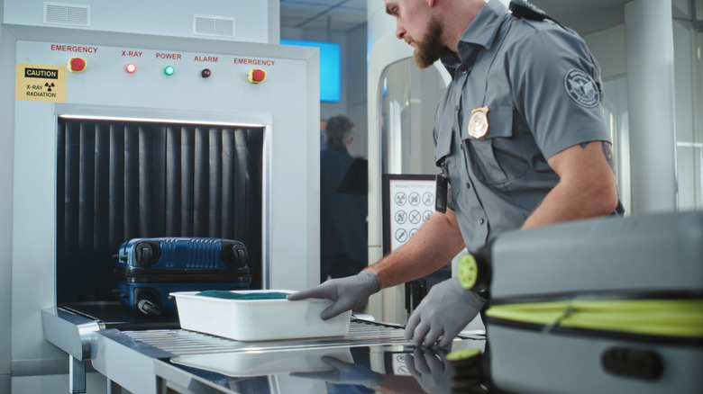 a TSA officer checking carry-on electronics and luggage