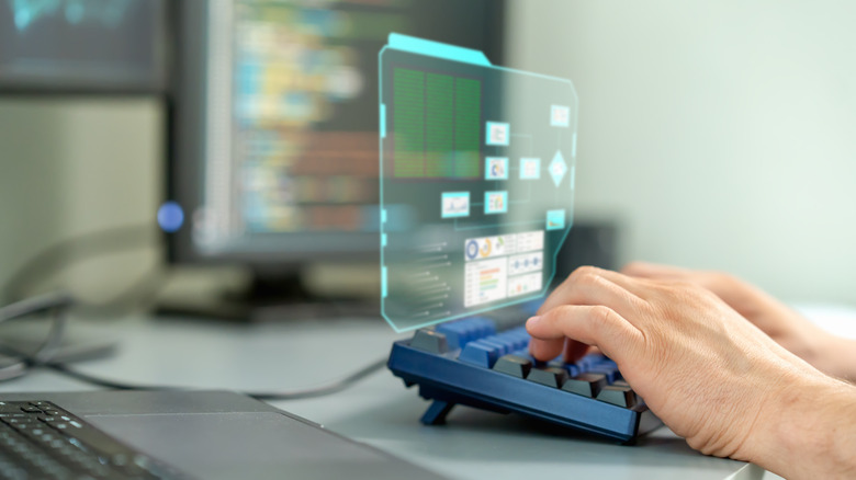 A close-up of male hands working on a desktop pc with a digitization display on the keyboard.