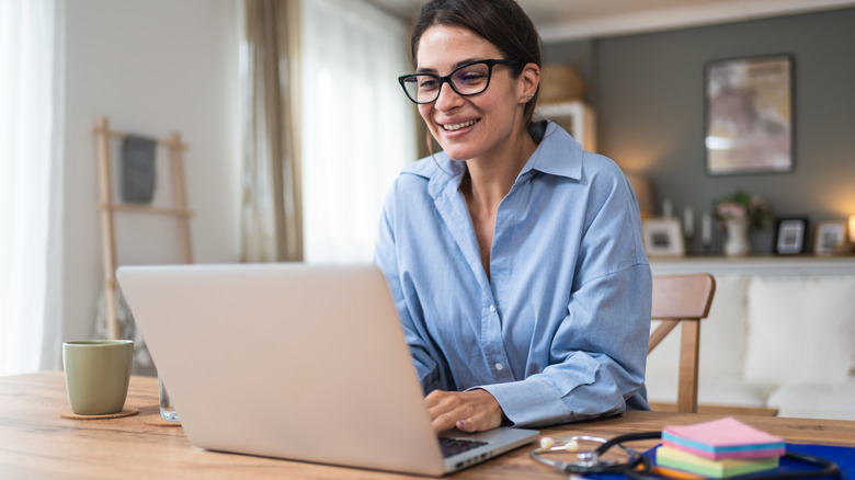 Young woman working at home office looking at a laptop screen