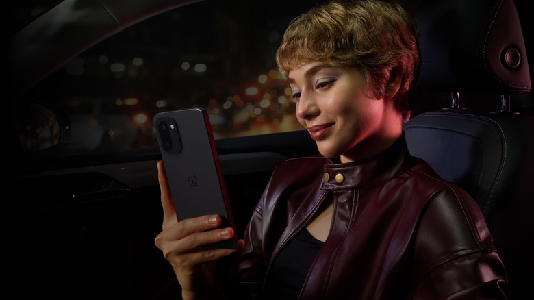 Woman holding a OnePlus 15 smartphone