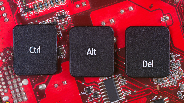 Keyboard keys for CTRL, ALT, and Delete on a red circuit board background.