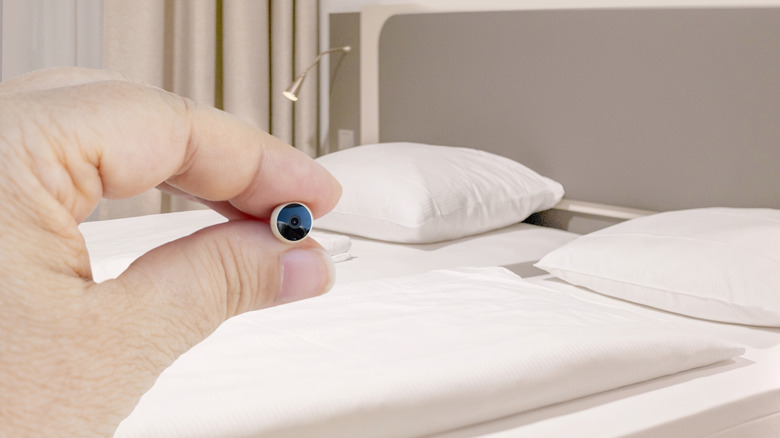A person holding a tiny spy camera in hand.