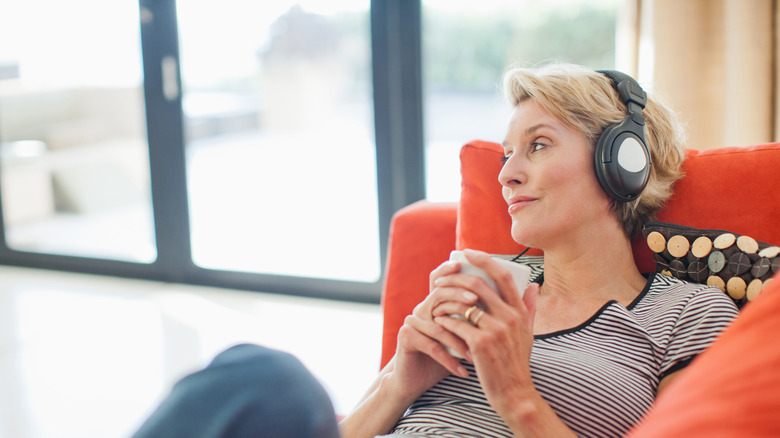 A woman wearing a pair of headphones and lying on a couch.