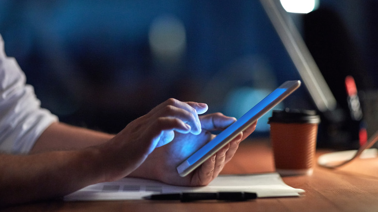 Someone using their tablet at a workspace with the screen on.