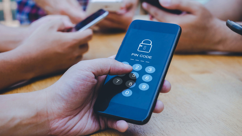 a phone prompting for a PIN code that a hand is holding