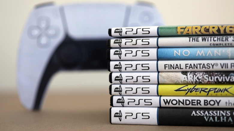 PlayStation 5 DualSense controller next to stack of game cases