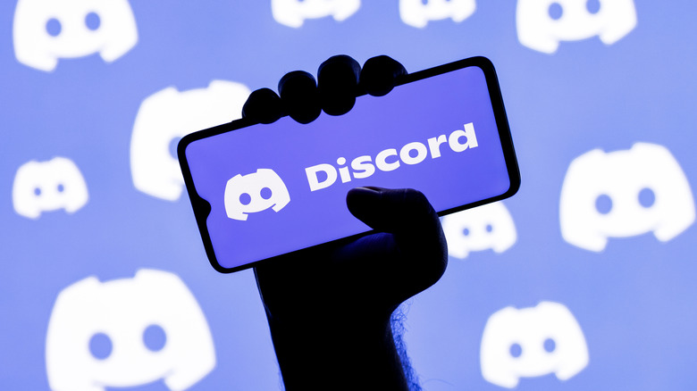 Person holding a phone running Discord with wallpaper of the Discord logo in the background