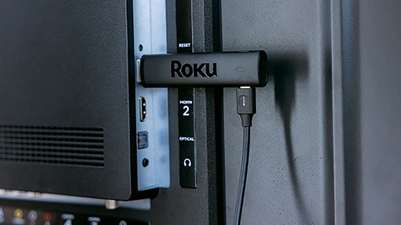 A Roku streaming stick plugged into the HDMI port of a TV