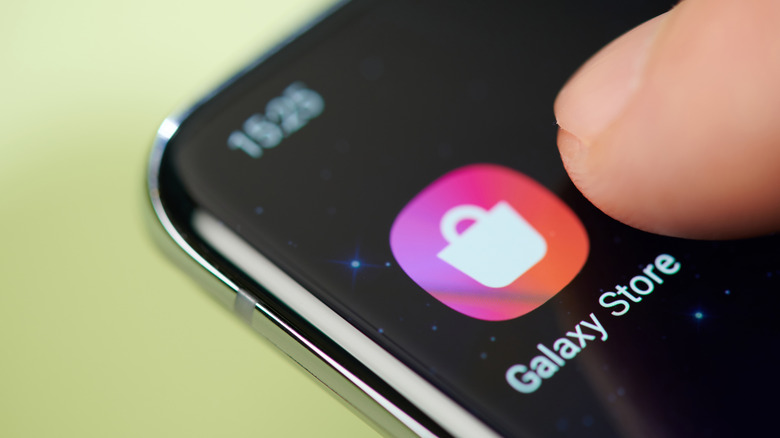 A finger pointing to the Galaxy Store app on a Samsung phone