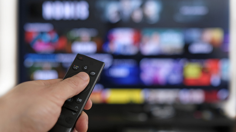 A person pointing a Samsung TV remote toward a Samsung TV