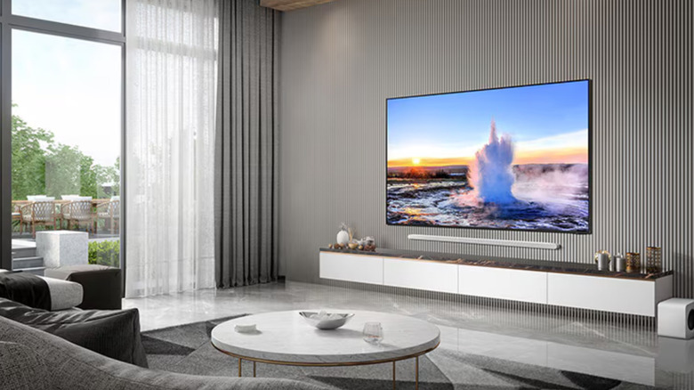 A Samsung TV wall-mounted in a modern living room above a wall-mounted soundbar and entertainment center