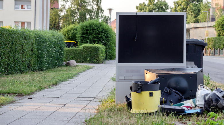 A TV thrown out with the garbage on a curb.