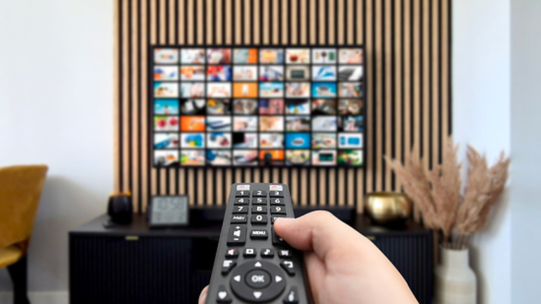 A person pointing a remote at a TV with apps displayed onscreen
