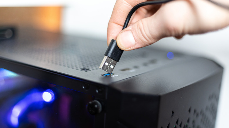 hand plugging in a USB cable to a computer