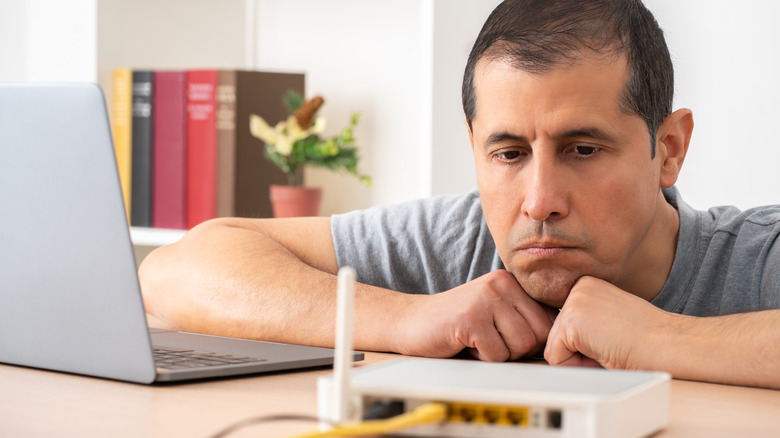 A man looks worryingly at his Wi-Fi router.
