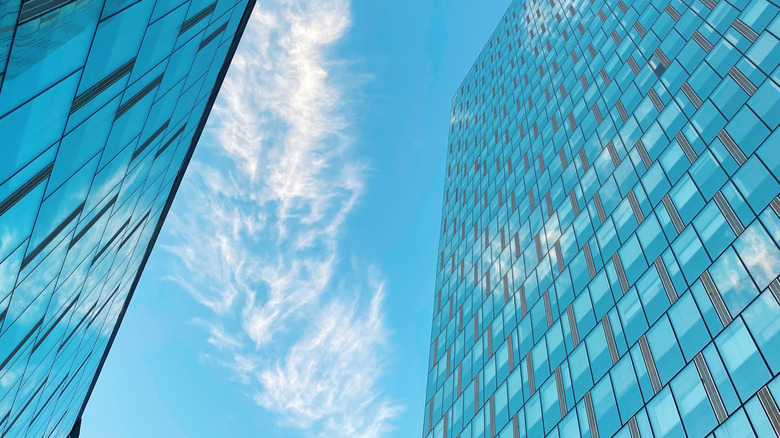 Two skyscrapers with windows and blue sky in background