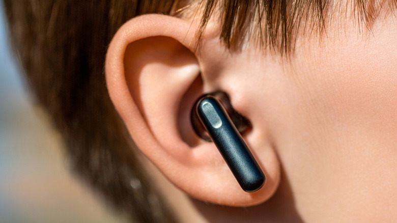Close-up of a man's head with black earbuds in his ears