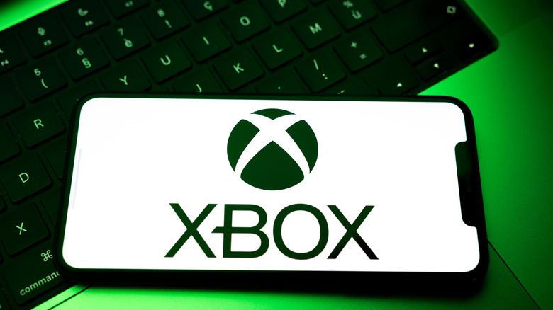 The Xbox logo on a phone atop a keyboard with green backlighting