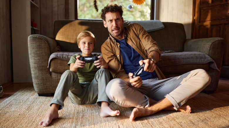 A man and child gaming on a PS4.