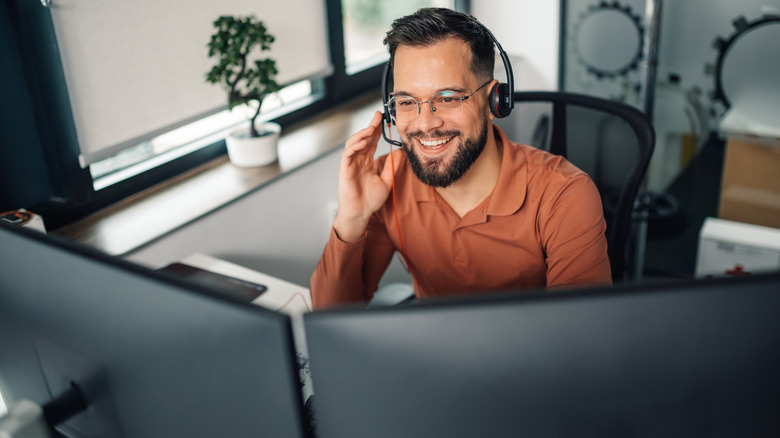 A man with a headset sitting at a desk in front of dual monitors