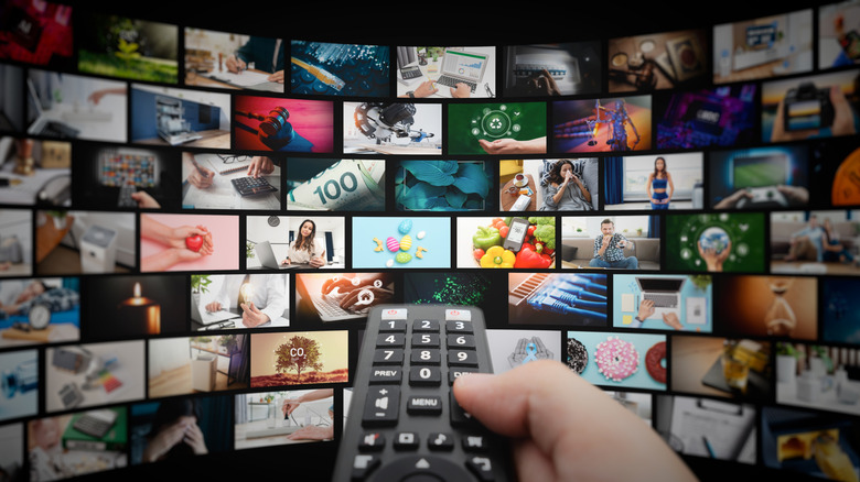person holding remote viewing multiple displays with different streams playing on it