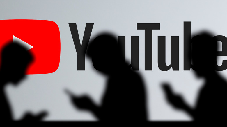 YouTube logo behind silhouettes of people using their phones