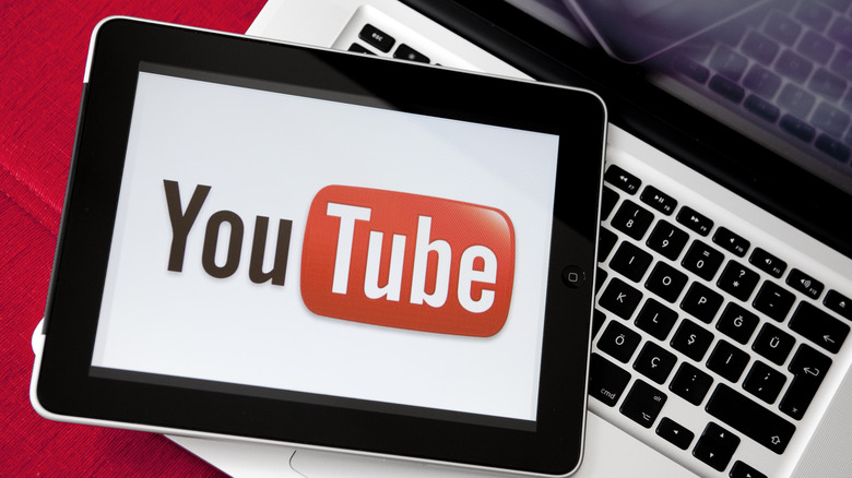 Youtube logo on an iPad screen resting on top of a MacBook keyboard