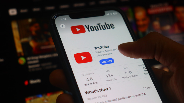 A person holding an iPhone with the Youtube app on the App Store