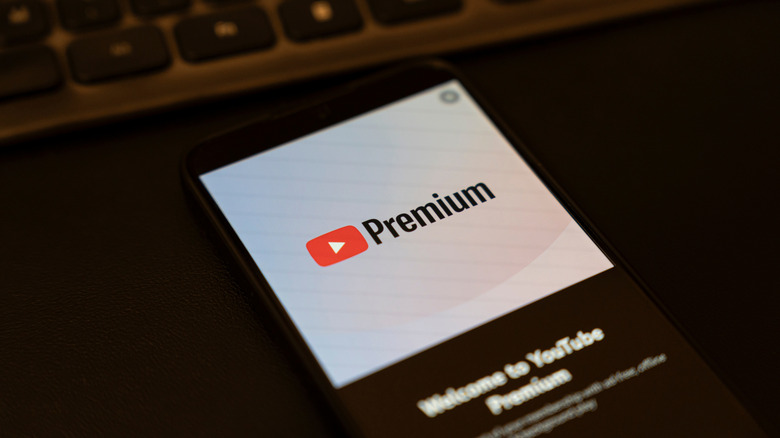 welcome to youtube premium notice on a smartphone with a keyboard visible in the background