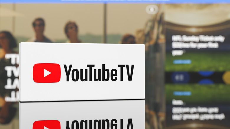 YouTube TV logo out front with UI of service in the background, blurred.